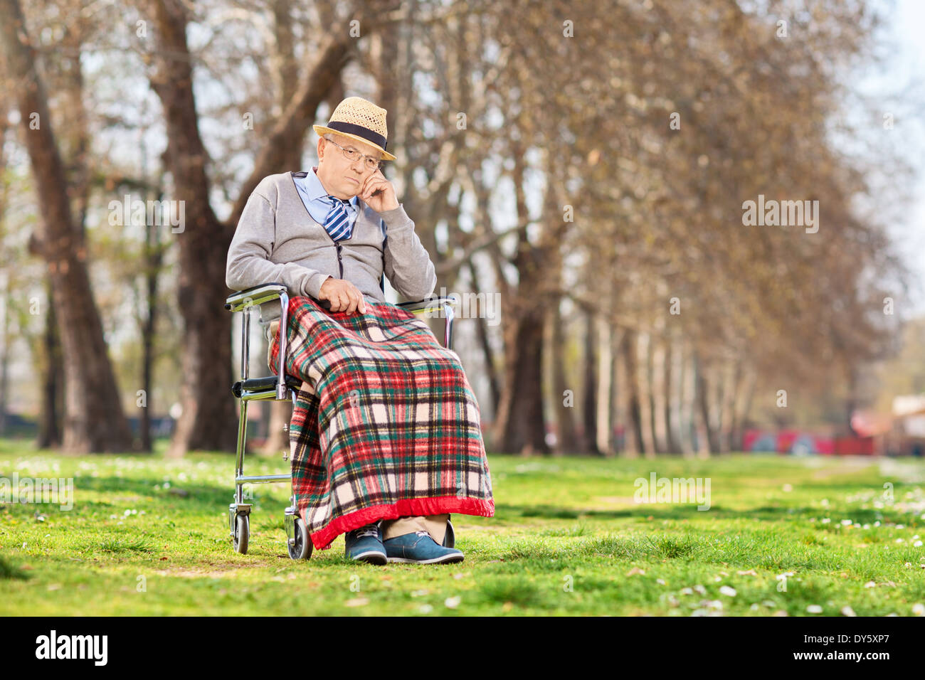 Grumpy Old homme assis dans un fauteuil roulant à l'extérieur Banque D'Images