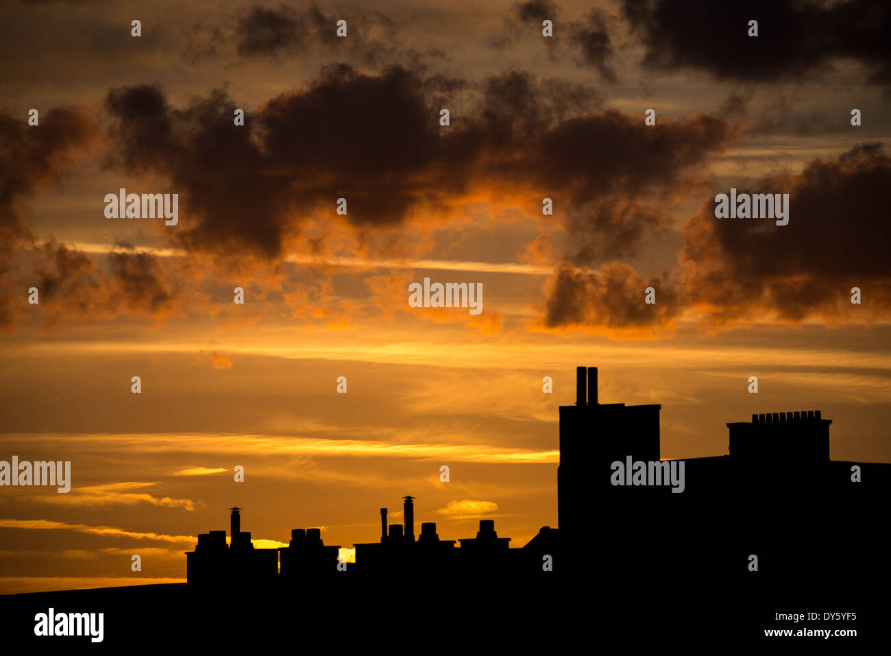 Silhouette de la ligne d'horizon de Bruxelles au coucher du soleil | BRUXELLES, Belgique — Les cheminées et les piles sur les toits se dressent en silhouette contre un coucher de soleil orange flamboyant sur la capitale belge. Les pots de cheminée traditionnels de ce genre restent courants au sommet des maisons en briques en rangée de la ville, un héritage du chauffage au charbon et au bois dans les quartiers résidentiels plus anciens. Banque D'Images