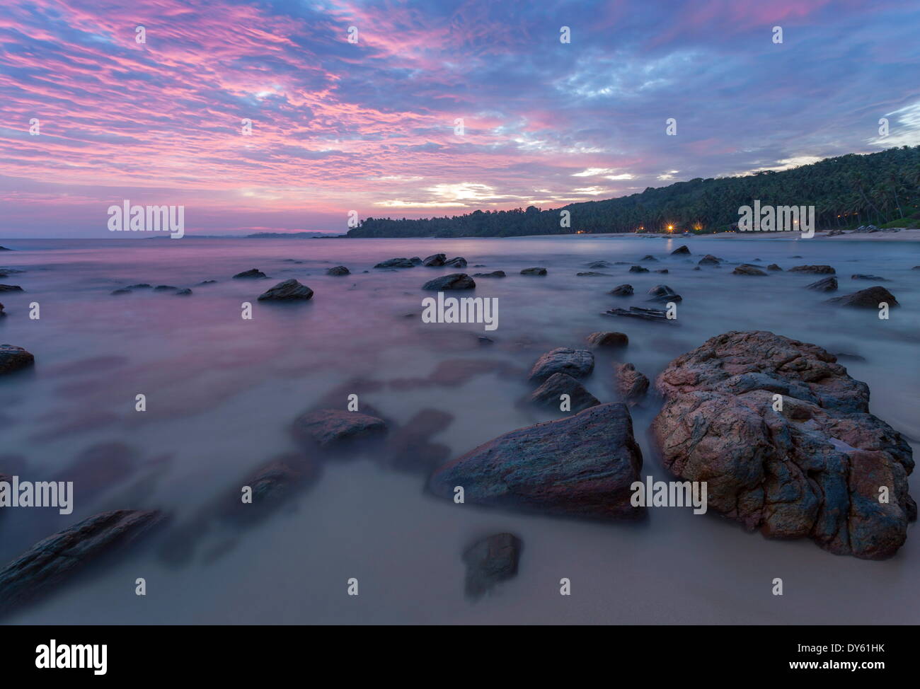 Une longue exposition d'un coucher de soleil rose sur la plage avec des rochers au crépuscule de l'avant-plan, Tangalle, au Sri Lanka, en Asie Banque D'Images