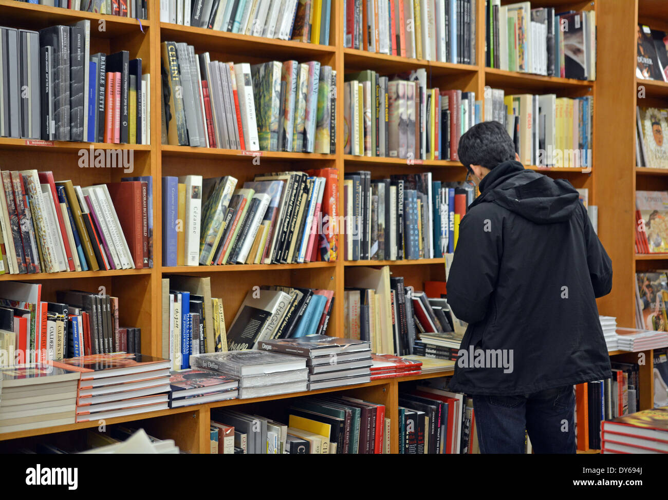 Un homme dans un manteau d'achats de livres à la librairie Strand à Broadway dans Greenwich Village, Manhattan, New York. Banque D'Images