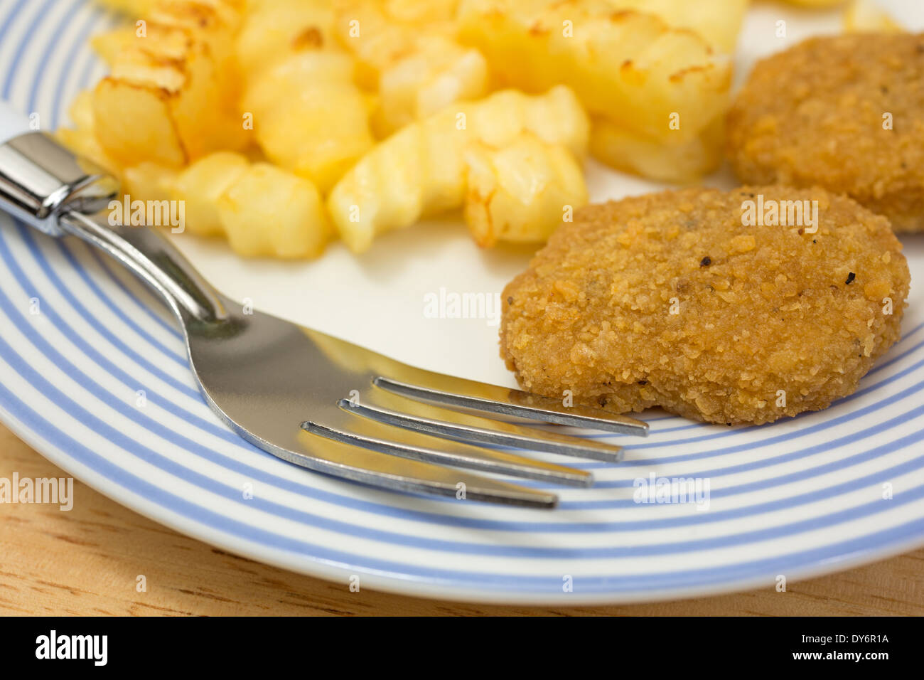 Fermer la vue d'un repas de croquettes de poulet avec frites sur une assiette avec une fourchette. Banque D'Images