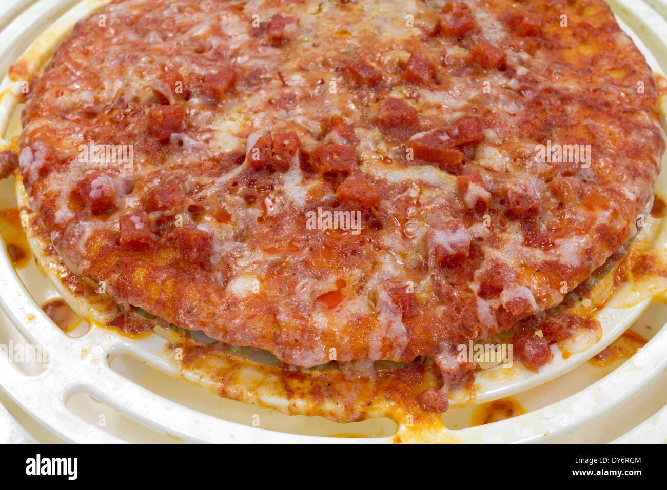 Une vue très proche d'une pizza trop cuite au four à micro-ondes montrant le désordre. Banque D'Images