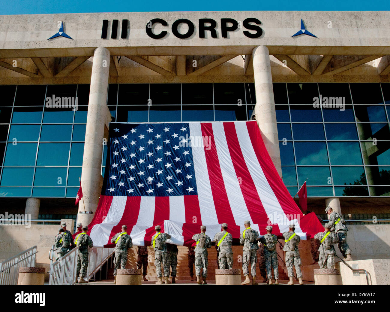 Les soldats de l'Armée de nous accrocher un drapeau américain géant du 3è Corps d'administration centrale en préparation pour un service commémoratif en hommage aux victimes de la fusillade du 7 avril 2014 à Fort Hood, Texas. Banque D'Images