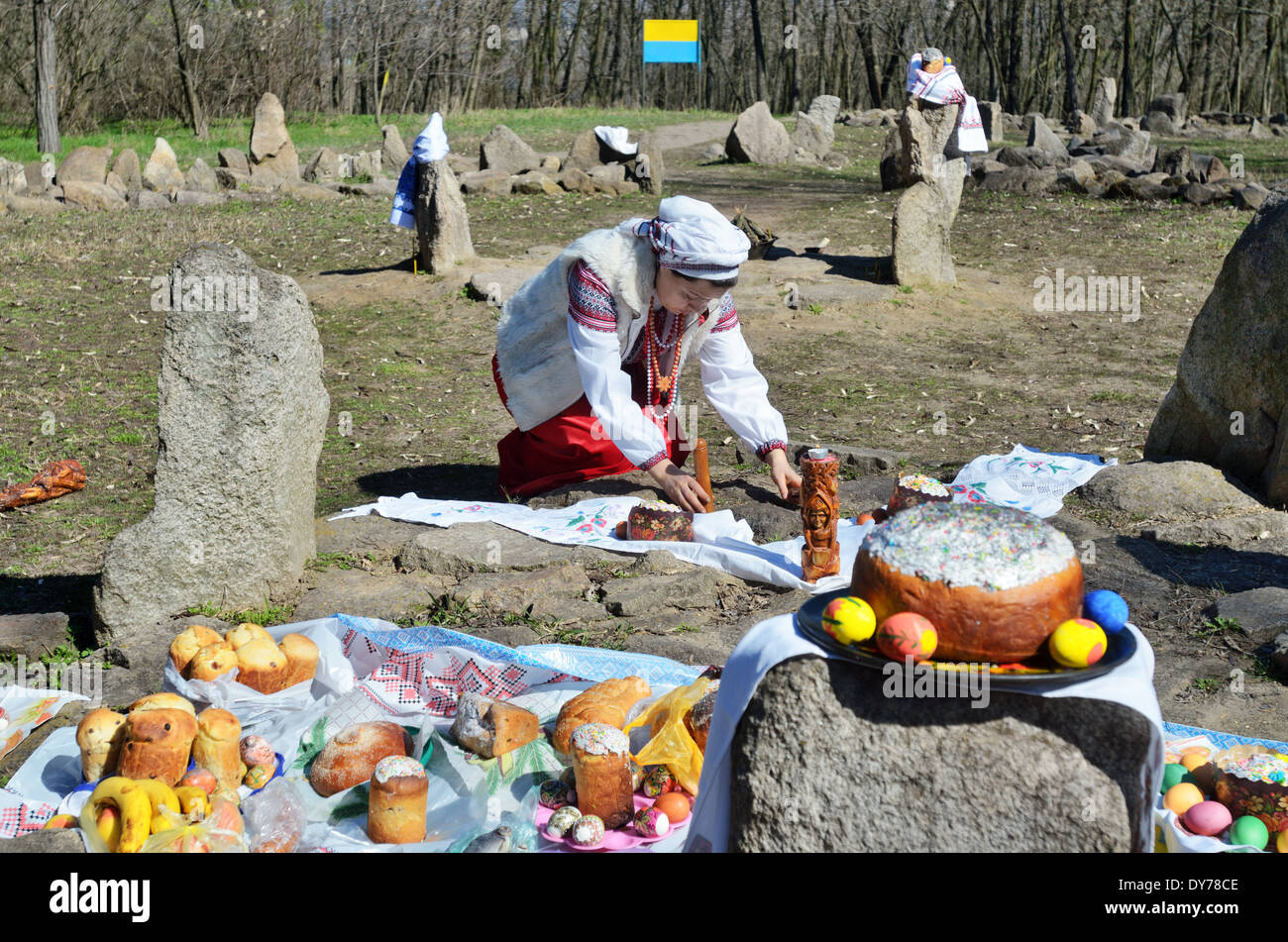 'Païen' Pâques en Ukraine. Préparation à la célébration de Pâques : Femme en vêtements traditionnels met l'alimentation et des idoles sur autel de pierre. Banque D'Images