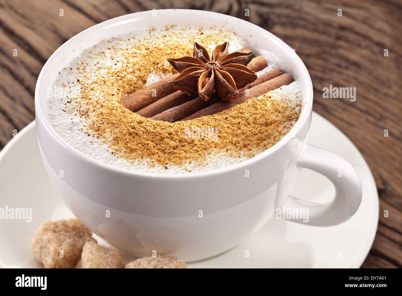 Tasse de cappuccino décoré avec des épices et des cubes de sucre brun près de lui. Banque D'Images