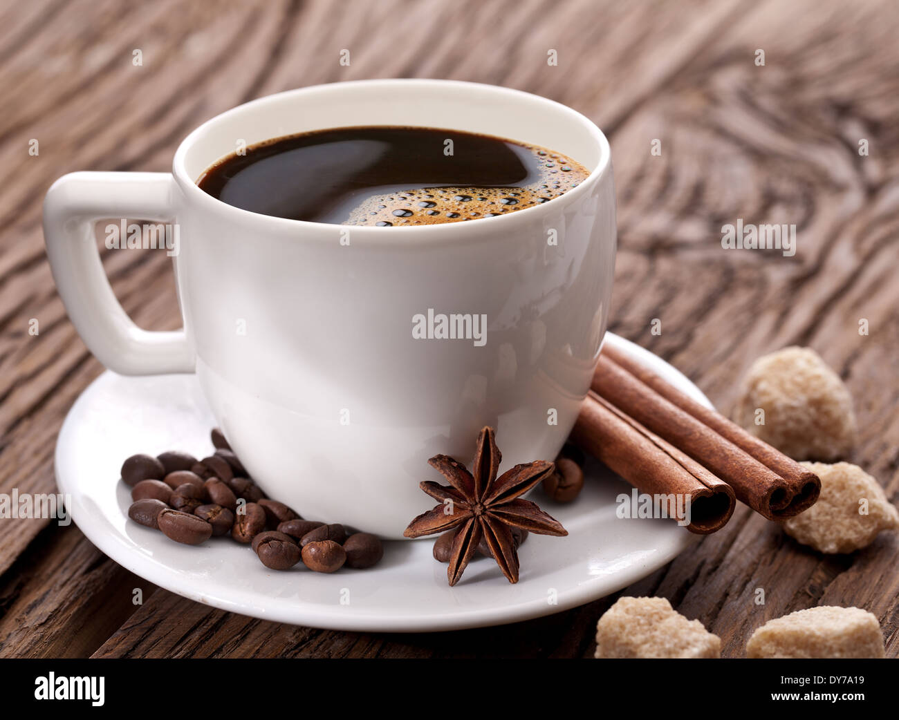 Tasse de café avec des grains de café et épices près de lui sur la vieille table en bois. Banque D'Images