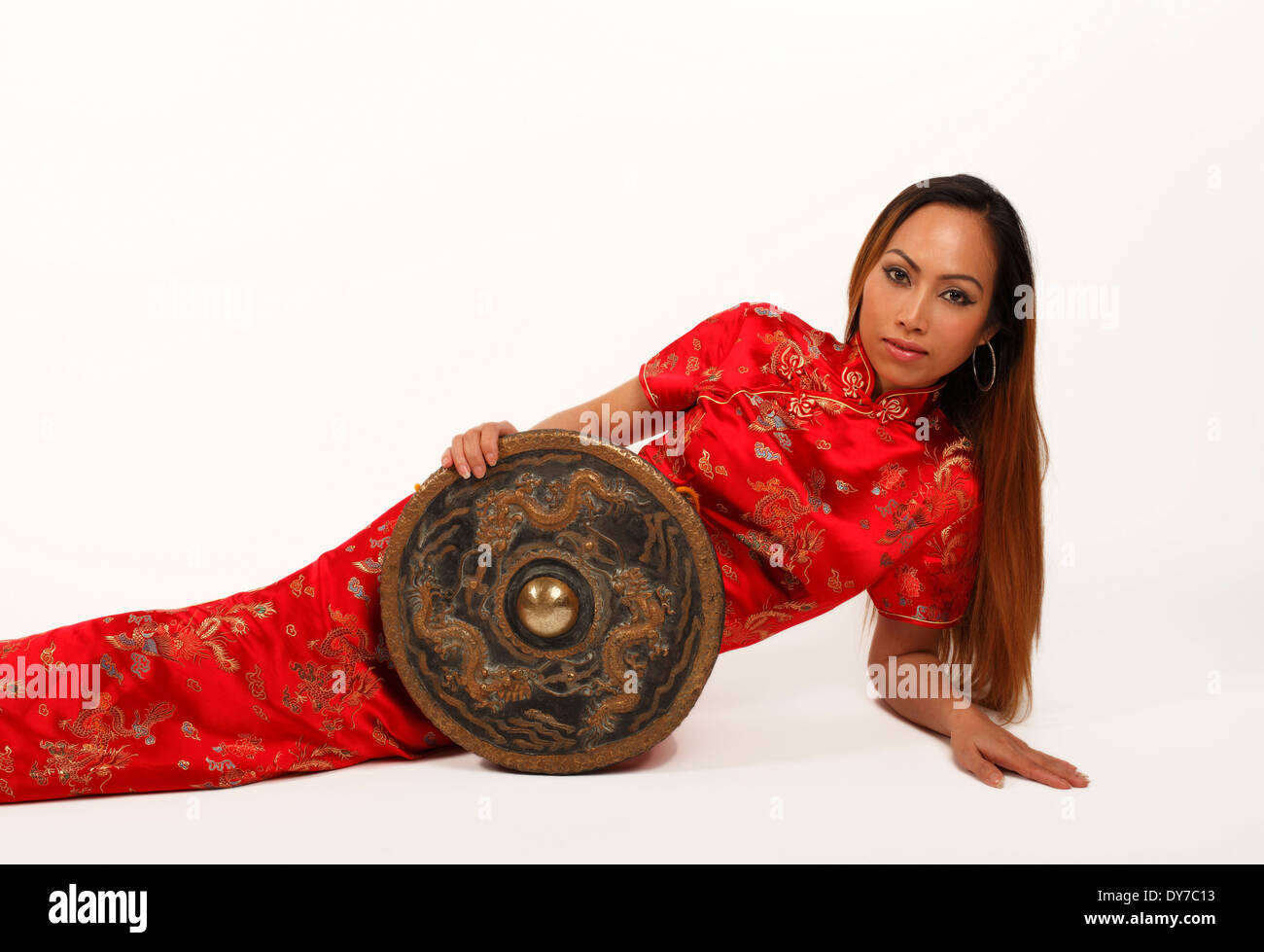 Gong chinois tenu par un asiatique ou oriental dame dans une robe traditionnelle rouge Banque D'Images