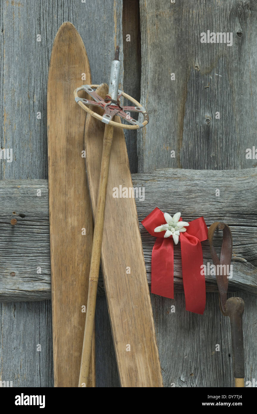 Vieux skis, bâton de ski arc rouge, à l'Edelweiss (Leontopodium alpinum) s'appuyant au mur en bois Banque D'Images