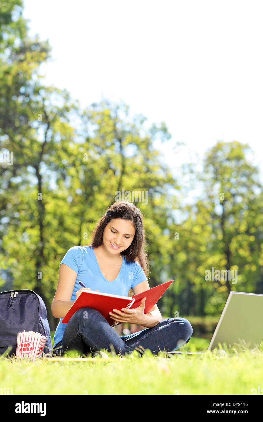 Élève écrit dans un cahier dans park Banque D'Images
