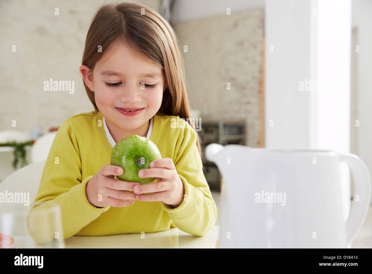 Allemagne, Munich, fille assise à table avec green apple Banque D'Images