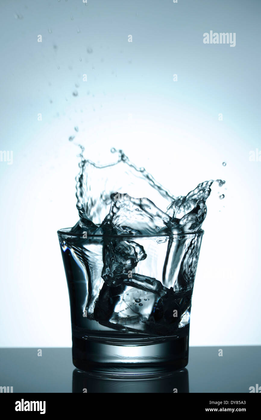 L'Icecube tomber dans un verre d'eau éclaboussant Banque D'Images