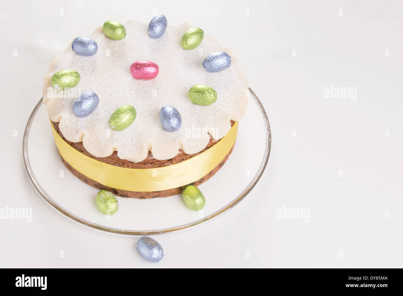 Simnel gâteau décoré avec du massepain et feuilles chocolat oeufs sur une plaque blanche avec fond blanc ( 20 sur 35) Banque D'Images