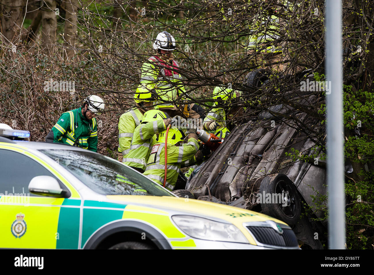Queenswood dur, Leeds West Yorkshire UK 9 avril 2014. Les services d'urgence assister à un incident survenu à autour de 14 heures dans lequel un véhicule s'est retourné dans une longue rue de banlieue. Deux personnes ont été coupées à l'abri de la voiture qui s'est retrouvée sur son toit dans un bois au bord de la route dans le parc Becketts zone LS6 et retiré de la scène en ambulance. Le West Yorkshire Air Ambulance a également assisté à la scène mais n'a pas été utilisée pour le transport des blessés. Un autre véhicule, une Seat Ibiza jaune, qui a été vu pour être endommagé a également été stationnée à proximité. Crédit : Ian Wray/Alamy Live News Banque D'Images