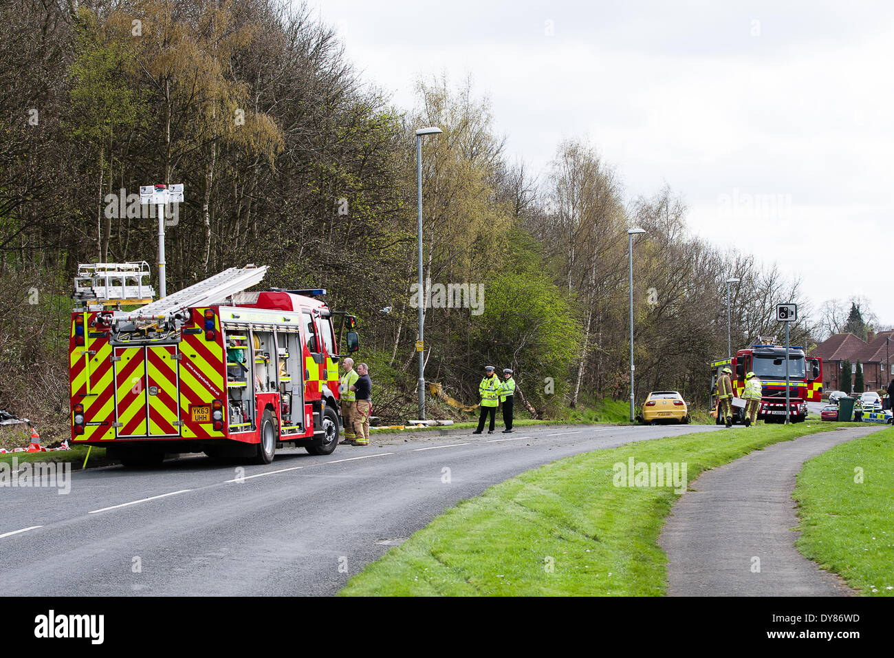 Queenswood dur, Leeds West Yorkshire UK 9 avril 2014. Les services d'urgence assister à un incident survenu à autour de 14 heures dans lequel un véhicule s'est retourné dans une longue rue de banlieue. Deux personnes ont été coupées à l'abri de la voiture qui s'est retrouvée sur son toit dans un bois au bord de la route dans le parc Becketts zone LS6 et retiré de la scène en ambulance. Le West Yorkshire Air Ambulance a également assisté à la scène mais n'a pas été utilisée pour le transport des blessés. Un autre véhicule, une Seat Ibiza jaune, qui a été vu pour être endommagé a également été stationnée à proximité. Crédit : Ian Wray/Alamy Live News Banque D'Images