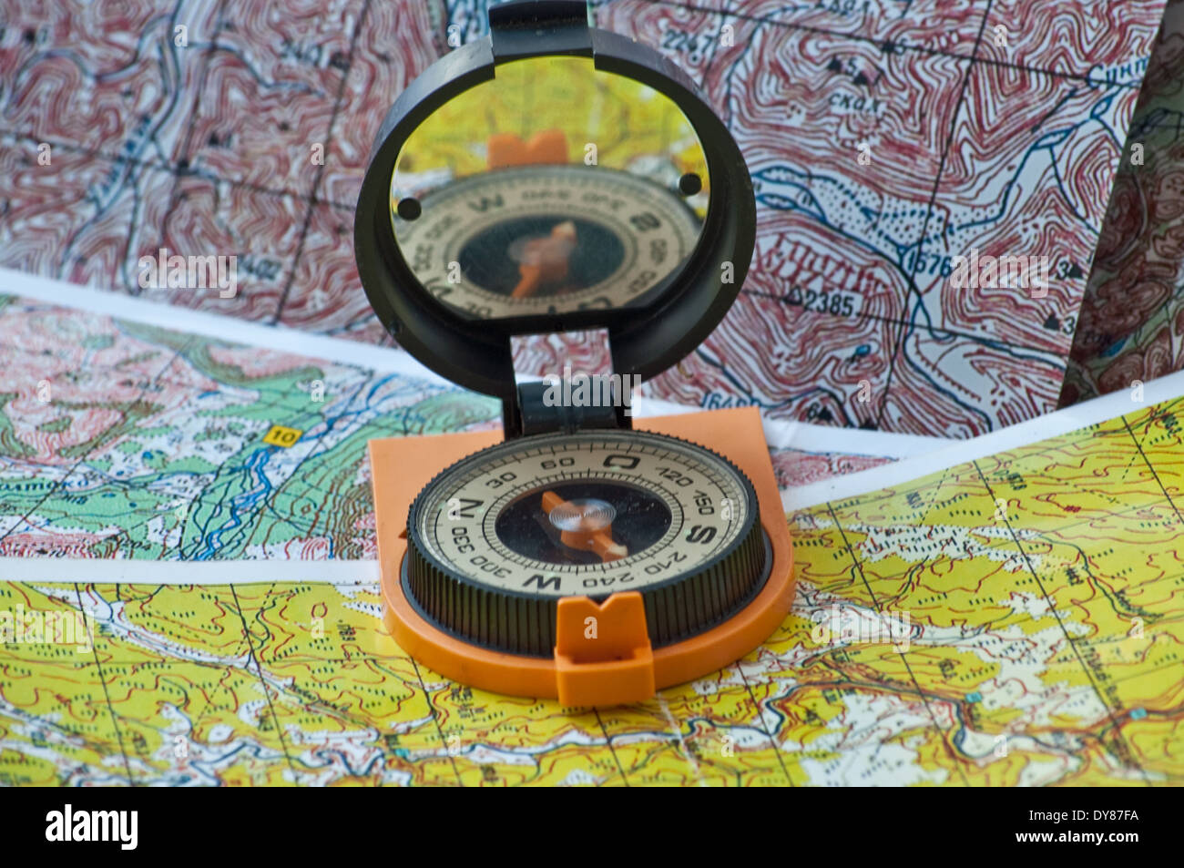 Compas magnétique dans un boîtier noir-rouge, équipé d'un miroir, est sur les cartes topographiques. Banque D'Images