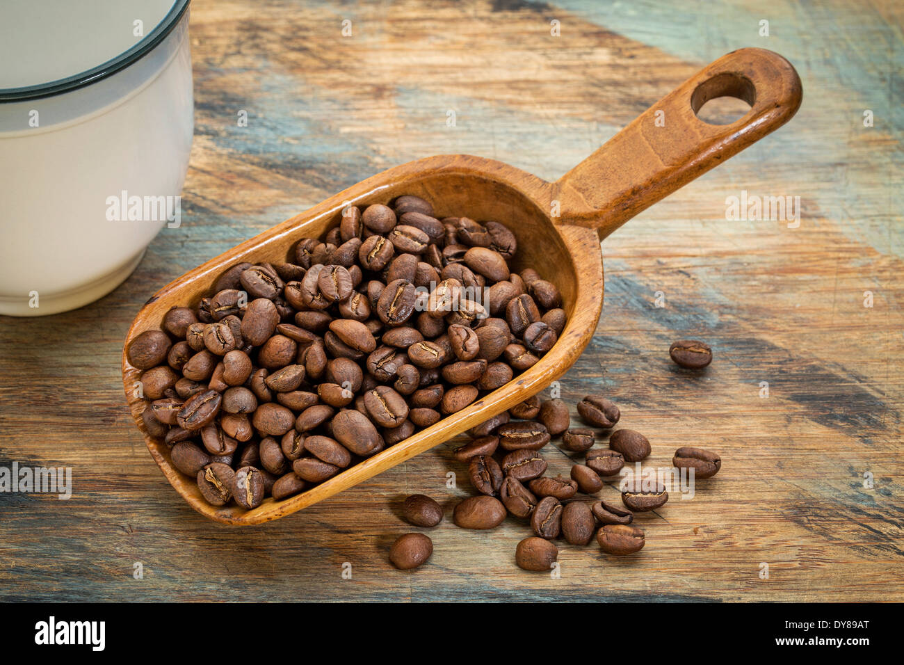 Scoop rustique de grains de café contre un arrière-plan en bois peint grunge Banque D'Images
