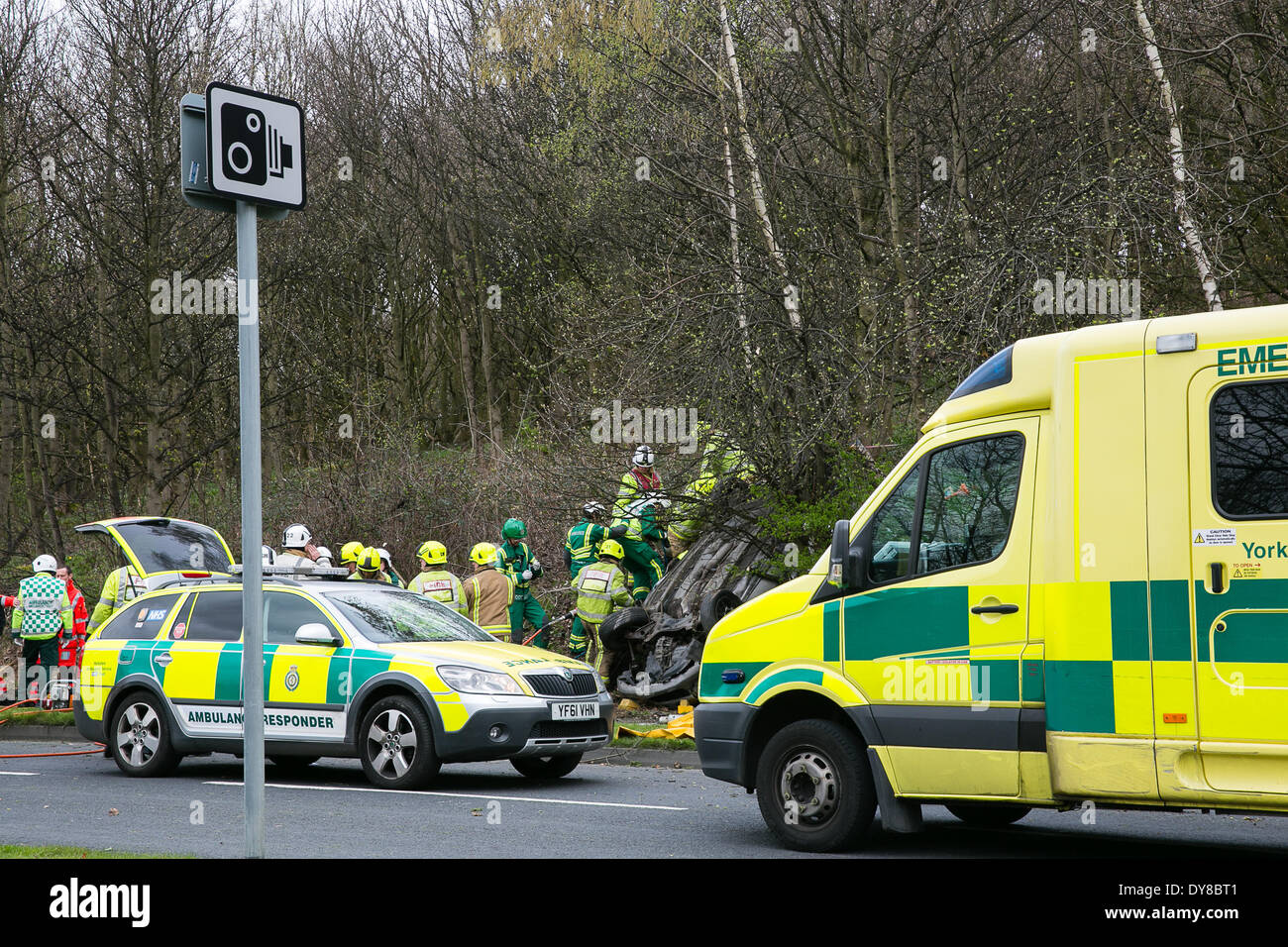 Queenswood dur, Leeds West Yorkshire UK 9 avril 2014. Les services d'urgence assister à un incident survenu à autour de 14 heures dans lequel un véhicule s'est retourné dans une longue rue de banlieue. Deux personnes ont été coupées à l'abri de la voiture qui s'est retrouvée sur son toit dans un bois au bord de la route dans le parc Becketts zone LS6 et retiré de la scène en ambulance. Le West Yorkshire Air Ambulance a également assisté à la scène mais n'a pas été utilisée pour le transport des blessés. Un autre véhicule, une Seat Ibiza jaune, qui a été vu pour être endommagé a également été stationnée à proximité. Crédit : Ian Wray/Alamy Live News Banque D'Images