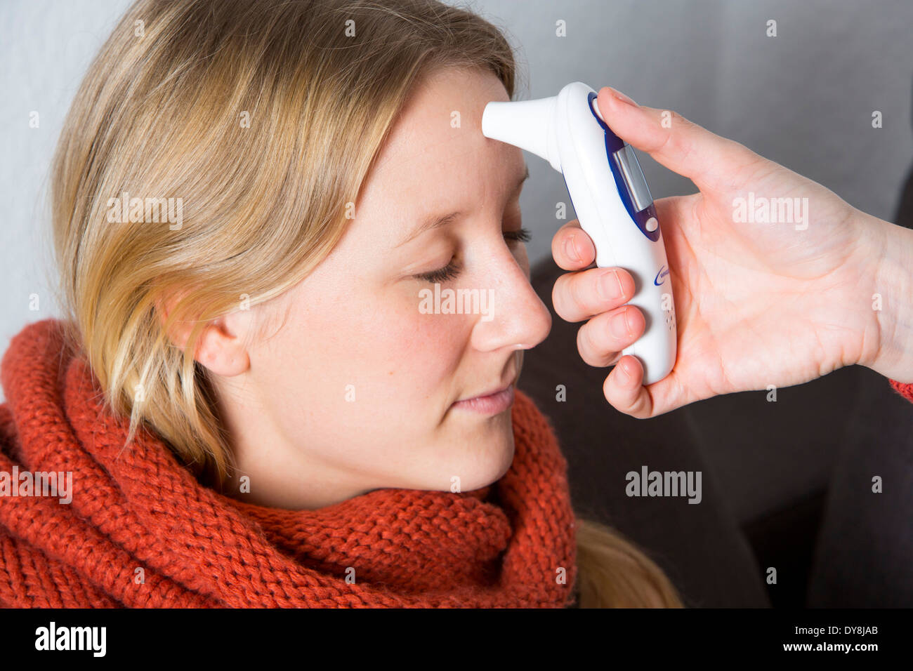 Jeune femme au lit, a un rhume, fièvre, grippe, fièvre, mesurée avec un thermomètre numérique Banque D'Images