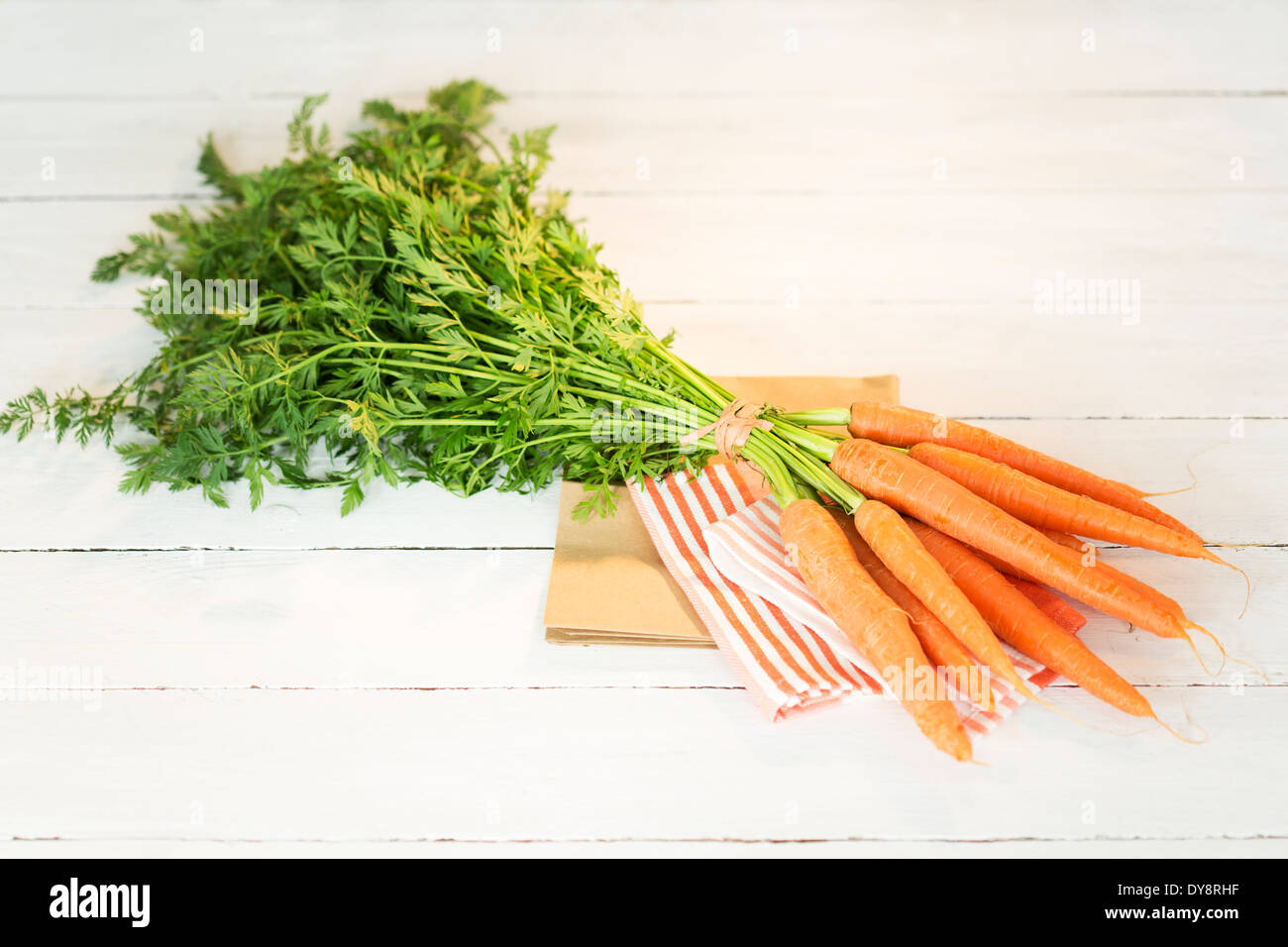 Botte de carottes biologiques sur le chiffon et table en bois blanc Banque D'Images