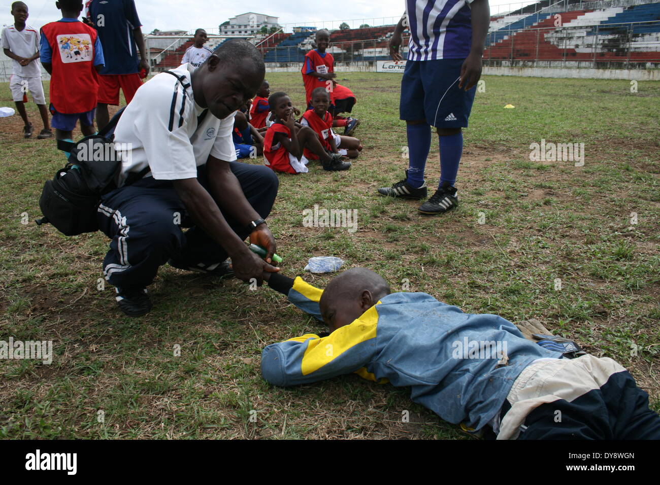 Wilson Cooper, médecin de l'équipe pour le National Youth Street Soccer Academy(NYSSA), des massages, un de ses joueurs à l'Antoinette Tu Banque D'Images