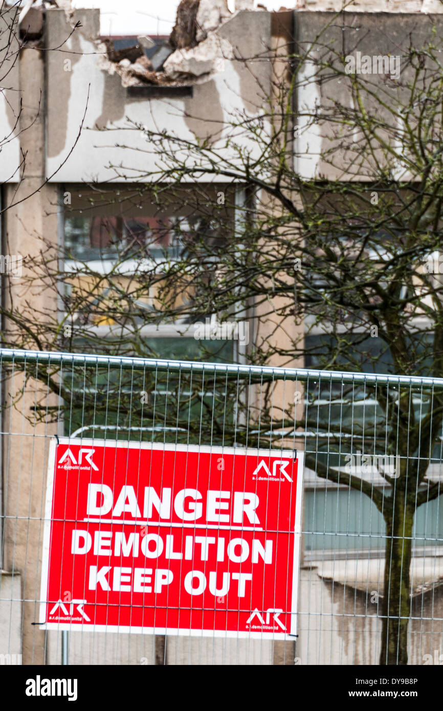 Tenir hors Démolition Danger sign attaché à une clôture entourant un chantier où un vieux bâtiment est démoli Banque D'Images