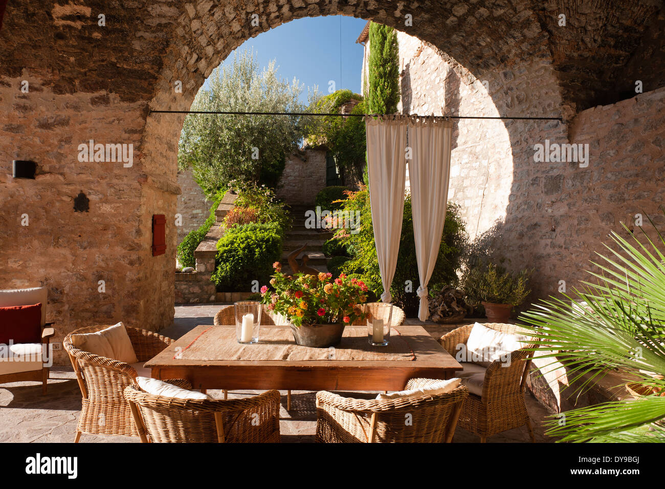 Patio couvert dans une ancienne villa italienne avec table en bois et des chaises en osier. Banque D'Images