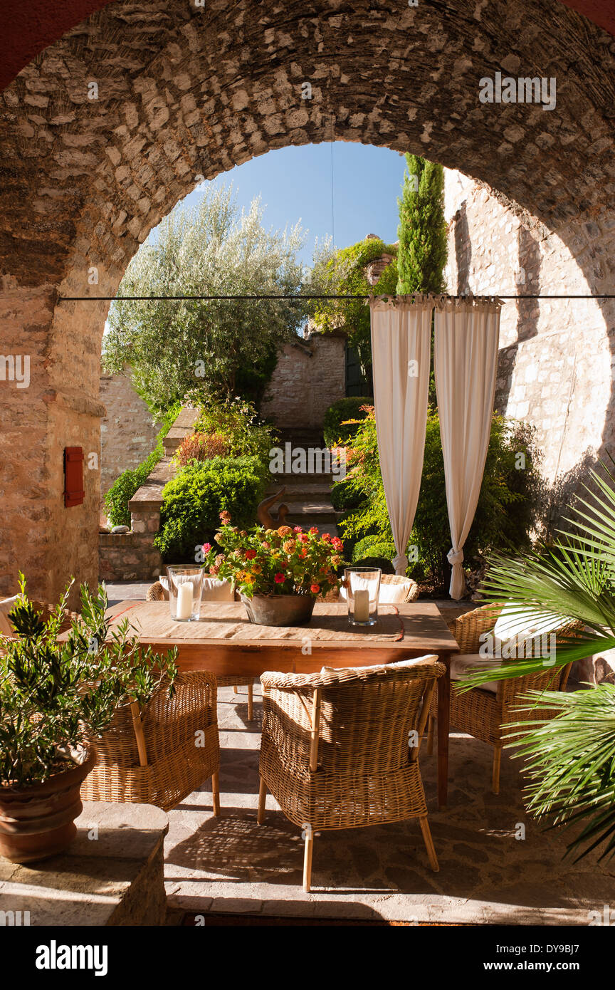 Patio couvert dans une ancienne villa italienne avec table en bois et des chaises en osier. Banque D'Images