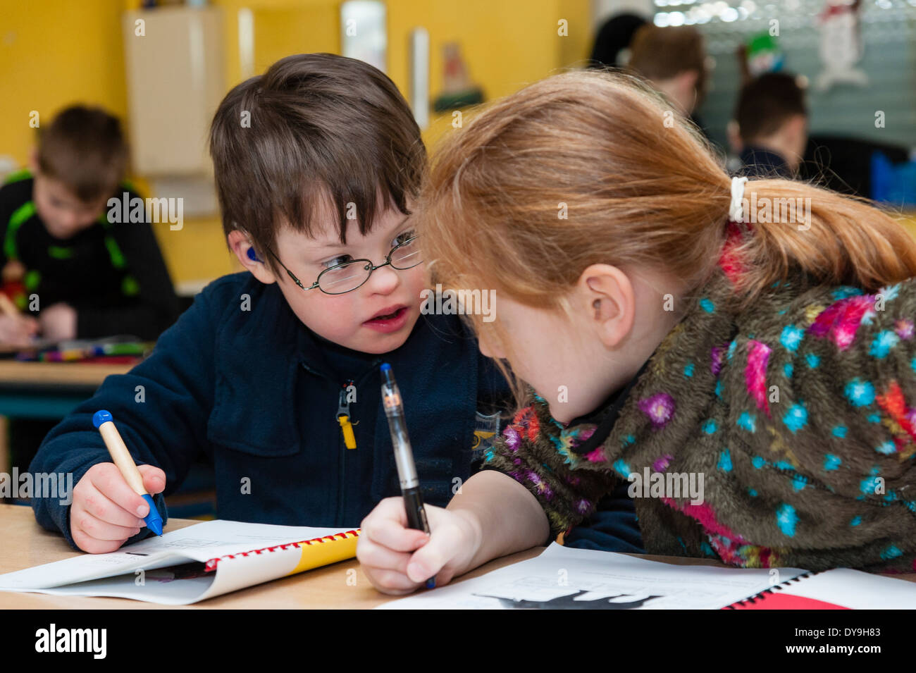 Les non-handicapés et élèves handicapés (dans ce cas, un garçon atteint de trisomie 21) apprendre ensemble dans la même classe. Banque D'Images