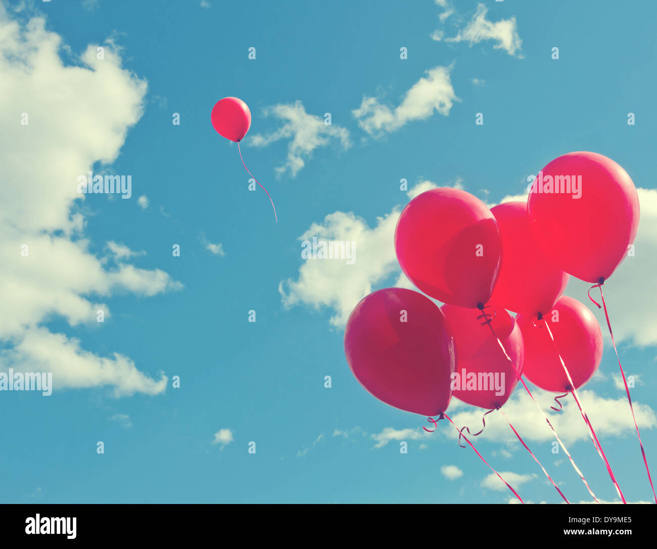 Bouquet de ballons rouges sur un ciel bleu avec un ballon s'échapper d'être individuel et gratuit - concept pour la suite de ses rêves Banque D'Images