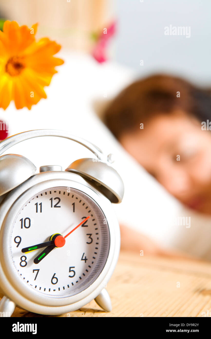 Vue rapprochée de l'horloge de table et d'une femme dormant sur retour Banque D'Images