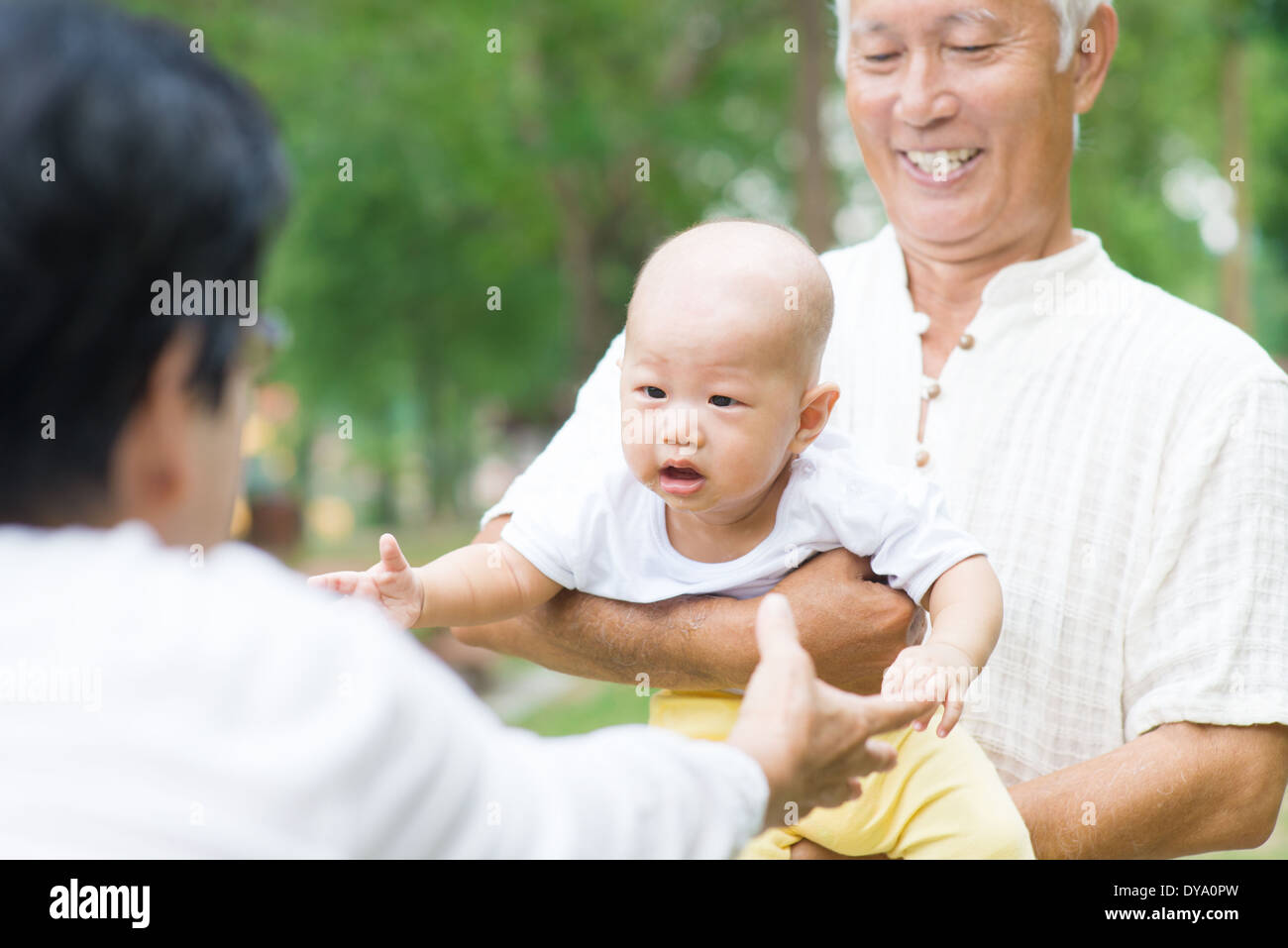 Les grands-parents d'Asie à jouer avec petit-fils bébé au jardin extérieur. Banque D'Images