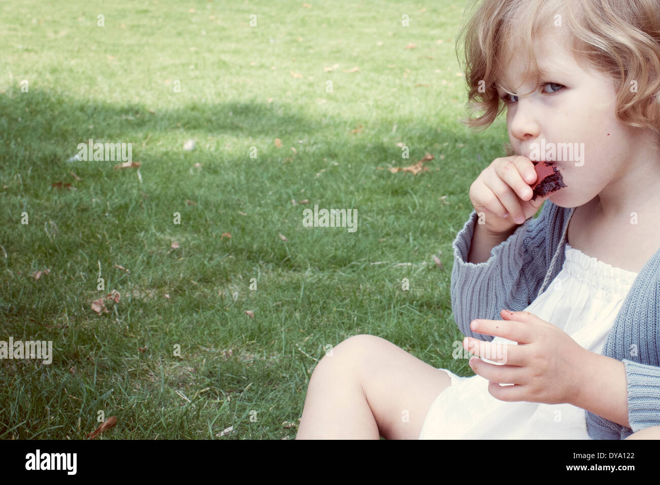 Little girl eating snack sucré à l'extérieur Banque D'Images