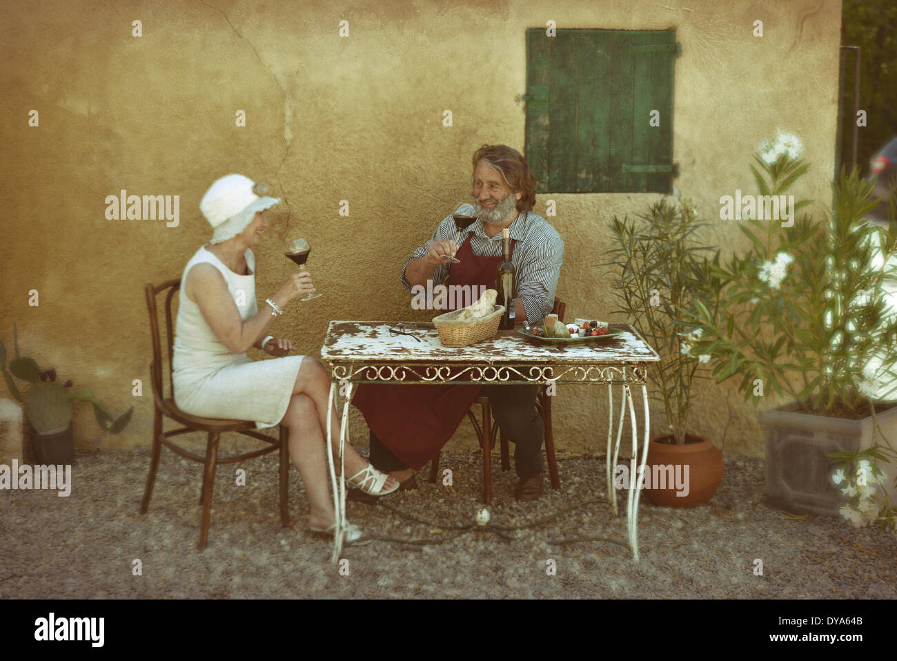 Europe France Provence vin de table français assis homme Saint Saturnin les Apt fleurs chien cour table vintage woman hat Banque D'Images