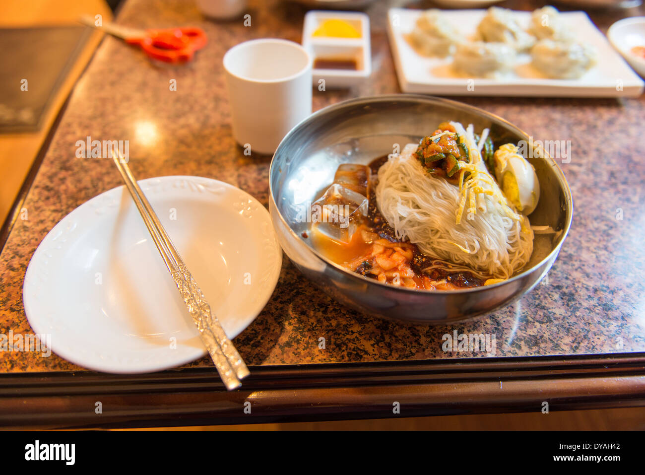 Bibim guksu, glace coréenne nouilles dans un bol en métal dans un restaurant coréen Banque D'Images