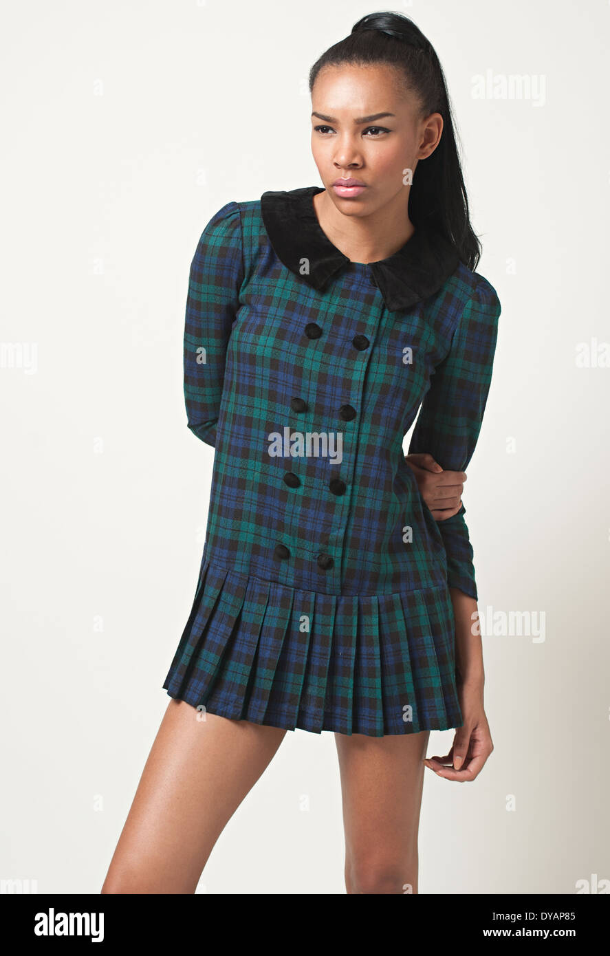 Une femme avec des cheveux noir queue, African American female mannequin portant un mod 60s bleu vert plaid mini dress posing Banque D'Images