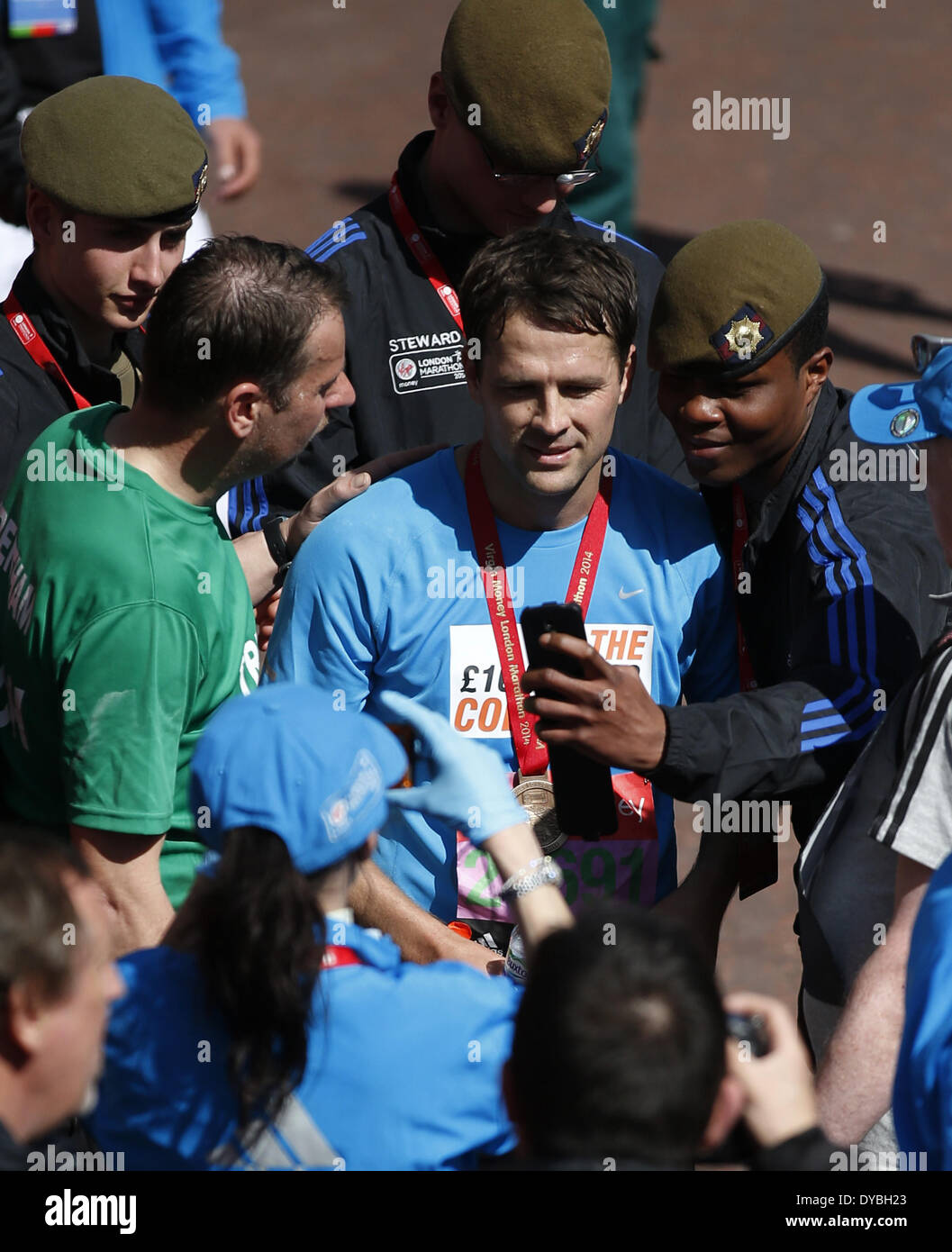 Londres, Marathon de Londres à Londres. 13 avr, 2014. Michael Owen, footballeur anglais, pose avec les fans pour une photo selfies après avoir franchi la ligne d'arrivée du Marathon de Londres 2014 à Londres, Grande-Bretagne le 13 avril, 2014. Michael Owen a terminé la course du club, de charité et de bulletin de groupe avec 3 heures 45 minutes et 43 secondes. Credit : Xinhua /Wang Lili/Xinhua/Alamy Live News Banque D'Images