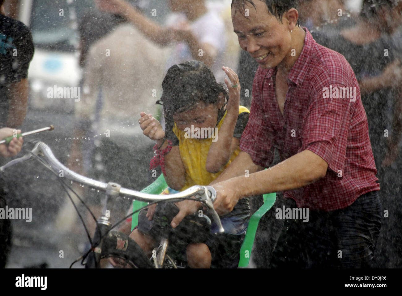 Yangon, Myanmar. 13 avr, 2014. Un homme et son enfant inscrivez-vous à la célébration de la fête de l'eau dans une rue de Yangon, Myanmar, le 13 avril 2014. L'eau du Myanmar Thingyan traditionnel Festival a fêté à Yangon le dimanche. (Xinhua/U Aung) Banque D'Images