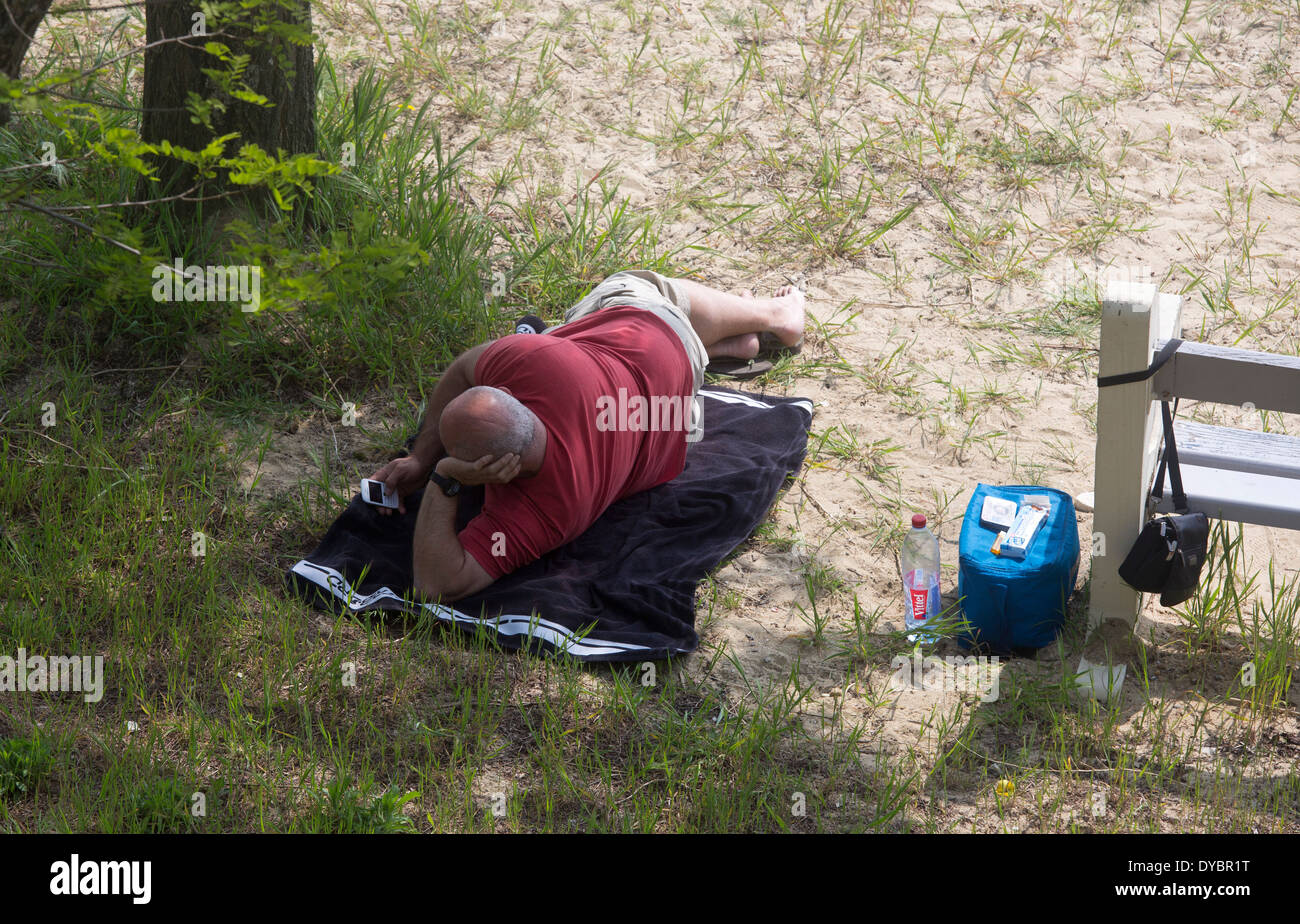 Homme d'âge moyen sur la plage à la recherche au seul téléphone Banque D'Images