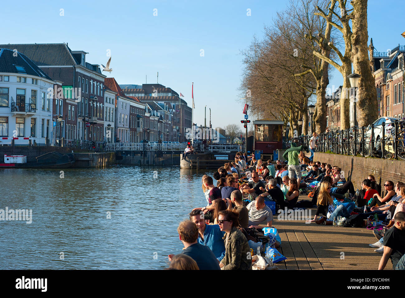 Les gens se détendre au soleil par un canal de la rivière dans le centre de Utrecht. Banque D'Images