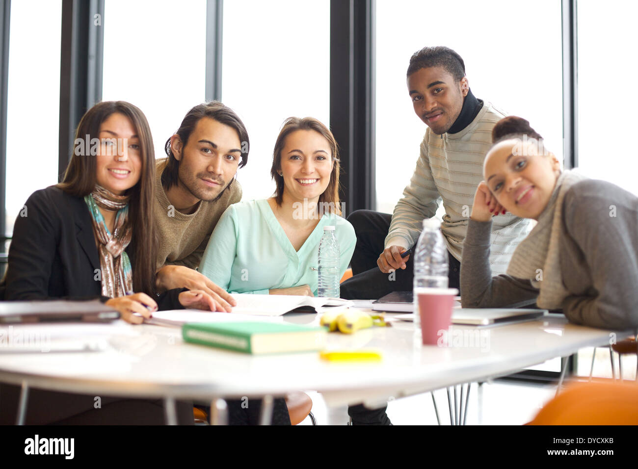 Portrait d'un groupe d'étudiants de l'université positive assis à table dans la bibliothèque. Mixed Race qui étudient ensemble dans la bibliothèque. Banque D'Images