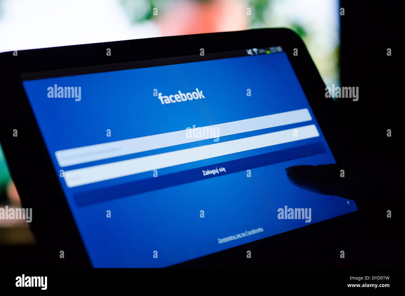 Woman pointing tablette avec l'application mobile de Facebook avec interface polonaise Banque D'Images