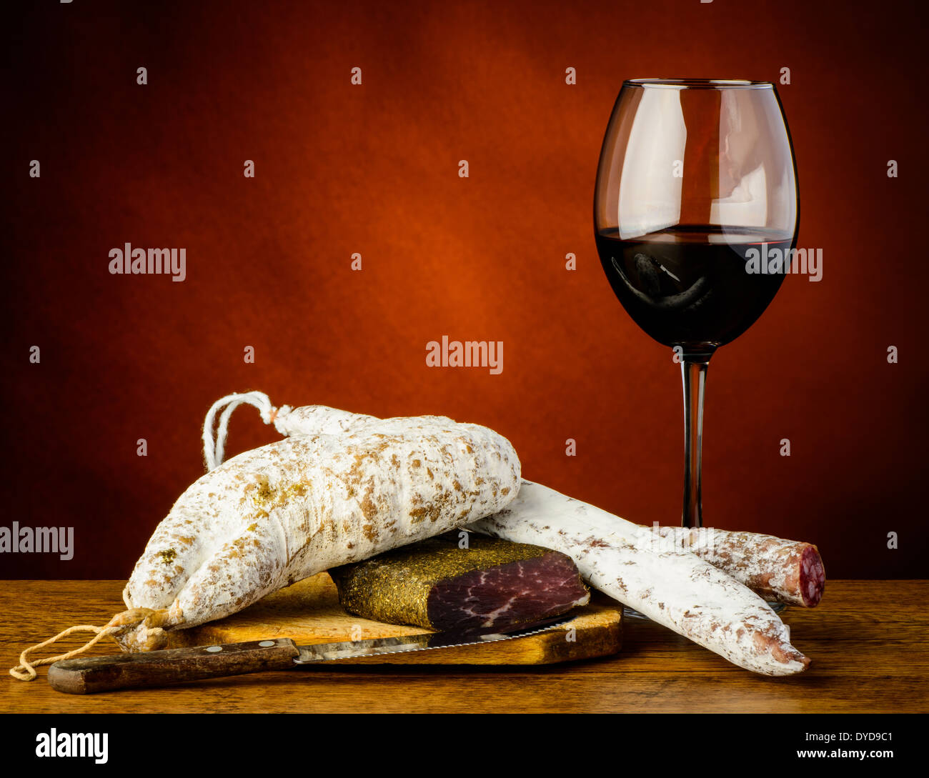 Verre de vin rouge et saucisses traditionnelles sur une plaque de bois Banque D'Images