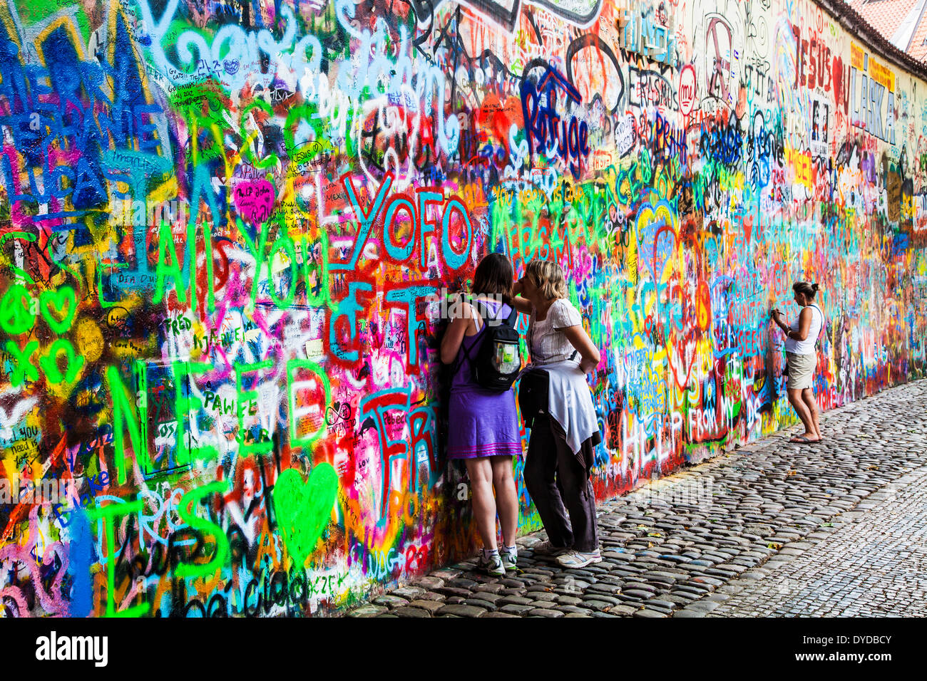 Deux femmes touristes ajouter graffiti au mur le John Lennon à Prague. Banque D'Images