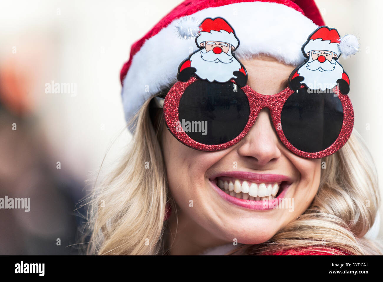 Une jolie femme portant des lunettes Noël nouveauté assistant à la Santacon annuel. Banque D'Images