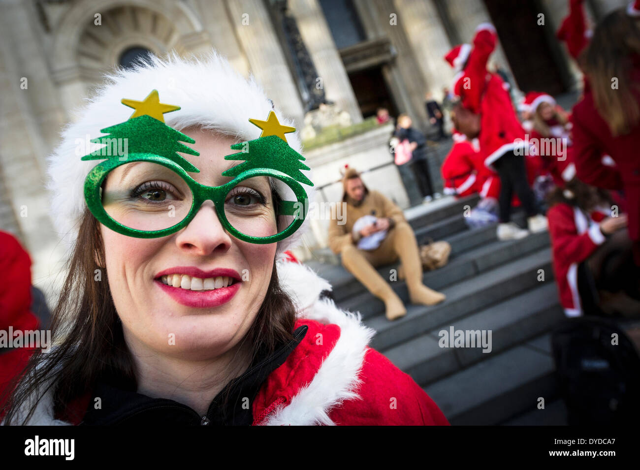 Une femme portant des lunettes nouveauté Santa comme des centaines de pères Noël se préparent à célébrer la Santacon annuel. Banque D'Images