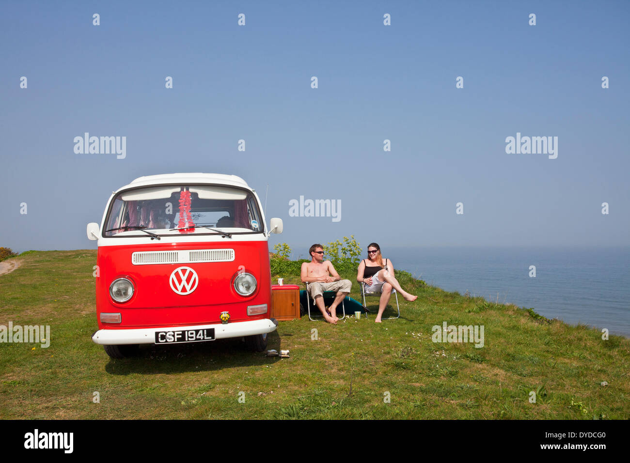 Un jeune couple camping dans un camping-car VW sur le clifftops sur sur la côte de Norfolk Mundesley. Banque D'Images