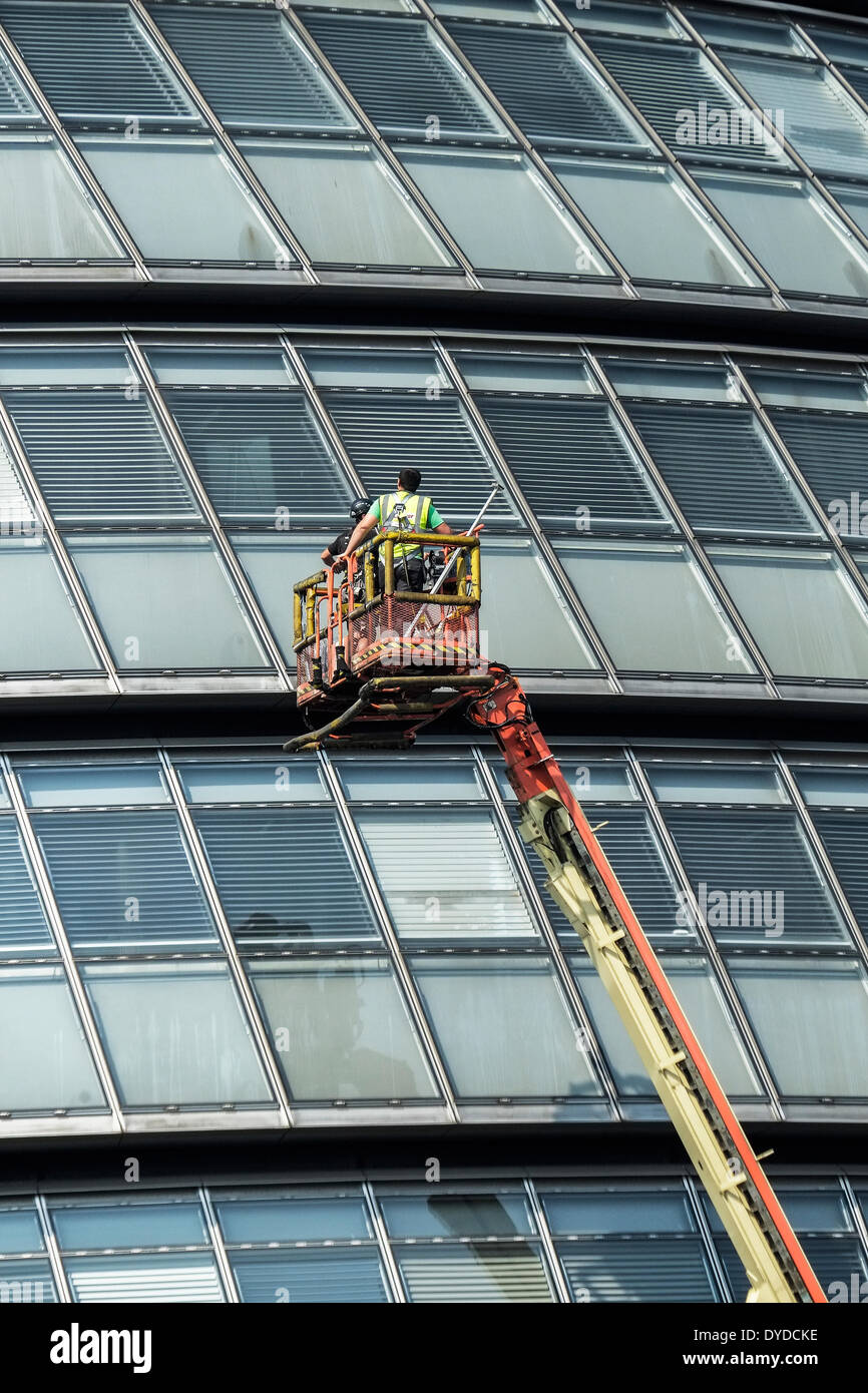 Les travailleurs sont levées au dessus de Londres l'Hôtel de ville pour effectuer des opérations d'entretien sur les fenêtres. Banque D'Images