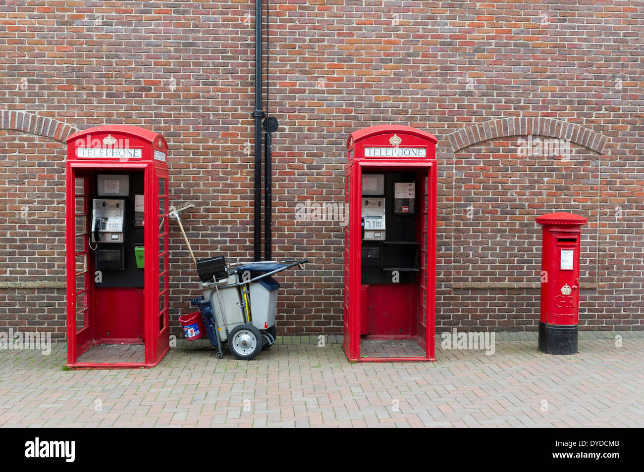 Deux cabines téléphoniques rouges traditionnel avec un pilier rouge fort et d'un chariot de nettoyage. Banque D'Images