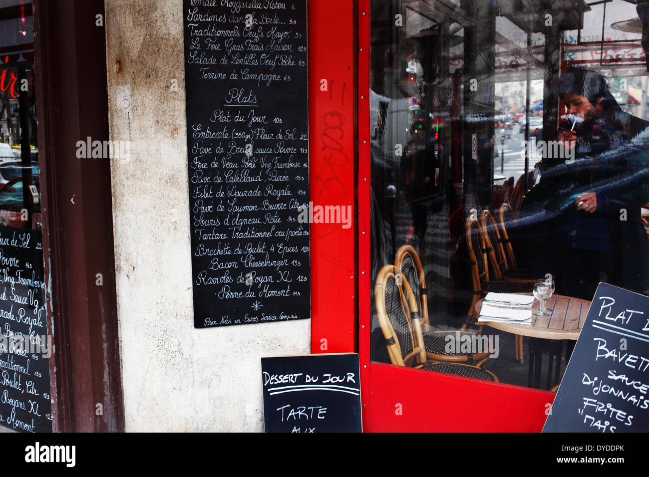 Un homme allumer une cigarette dans un café restaurant français sur le Boulevard Richard Lenoir. Banque D'Images