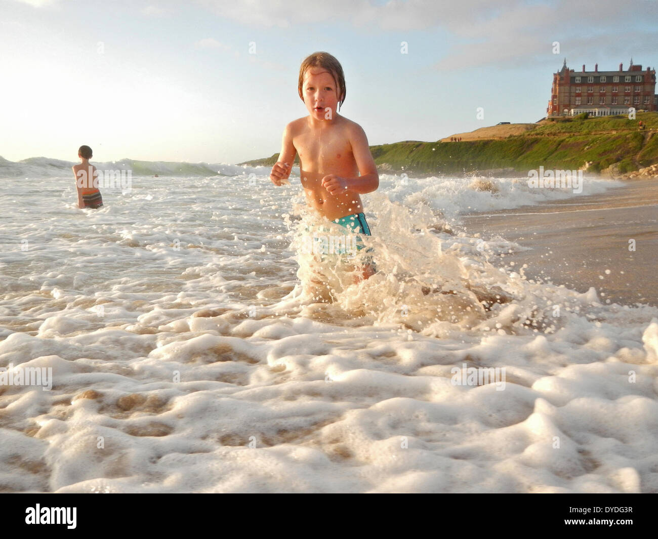 Un garçon heureux dans le surf à la plage de Fistral à Cornwall. Banque D'Images
